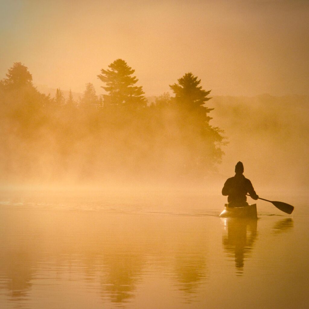 Paddler allein auf einem stillen See im Morgennebel
